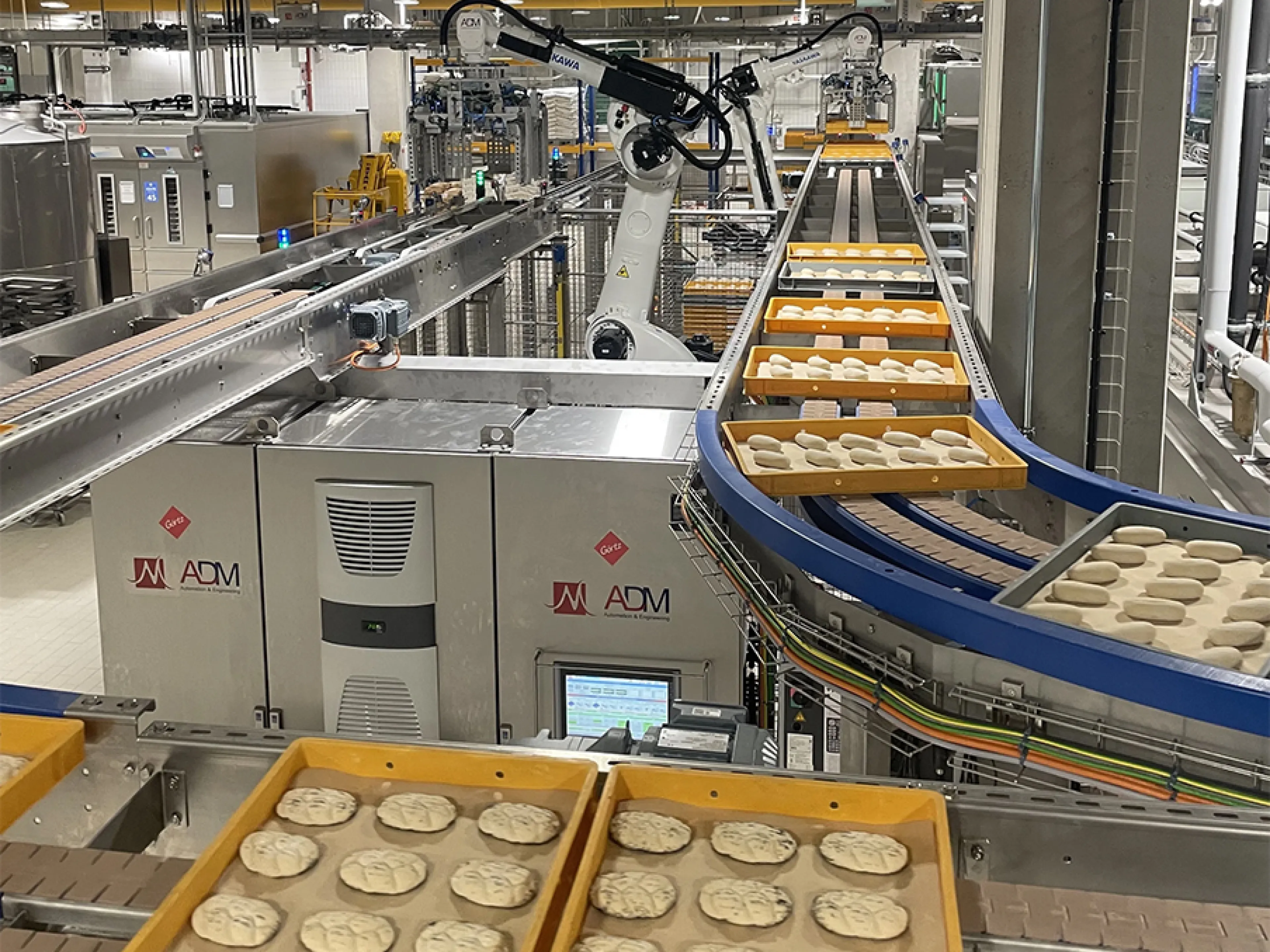 Zwei der vier „Motoman GP180“-Roboter entnehmen die Dielen am Frosterauslauf und setzen sie auf ein Förderband um, Bild: Yaskawa Zwei der vier „Motoman GP180“-Roboter entnehmen die Dielen am Frosterauslauf und setzen sie auf ein Förderband um.